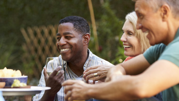 Group Of Mature Friends Enjoying Drinks In Backyard Together